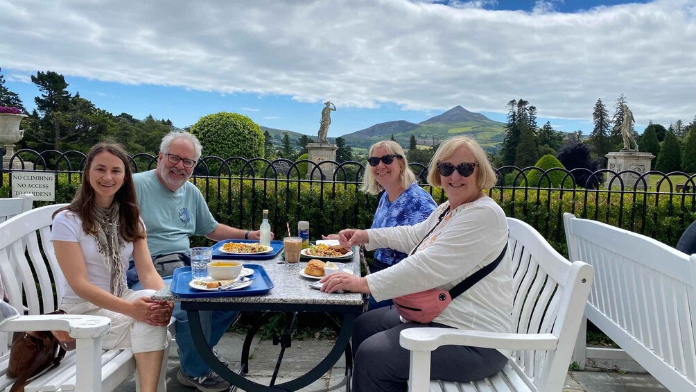 A group of people dining outdoors with a scenic mountain view in the background. 1