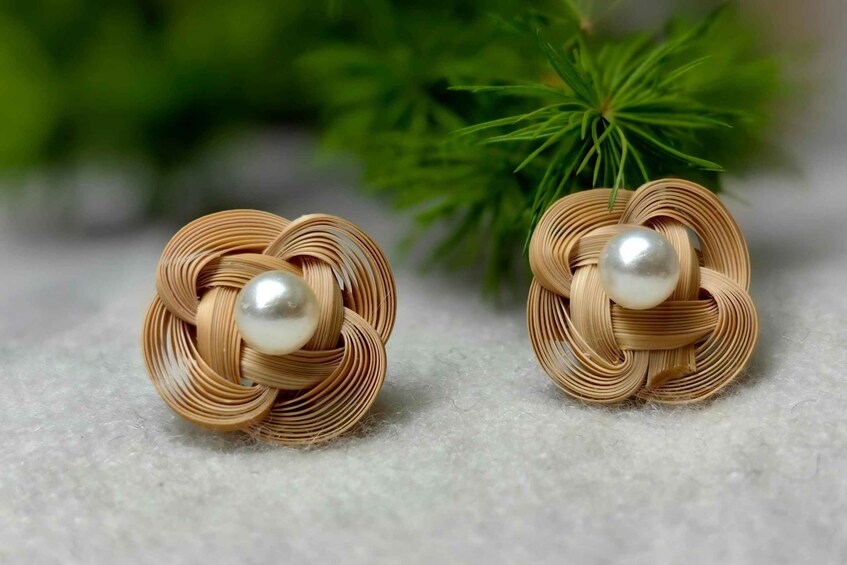 A pair of earrings with a woven design and a pearl. 5