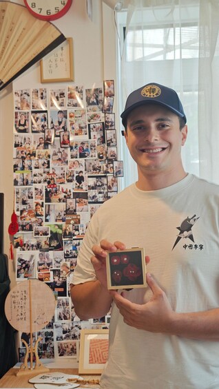 A person holding a framed picture in an office with a wall of photos. 2