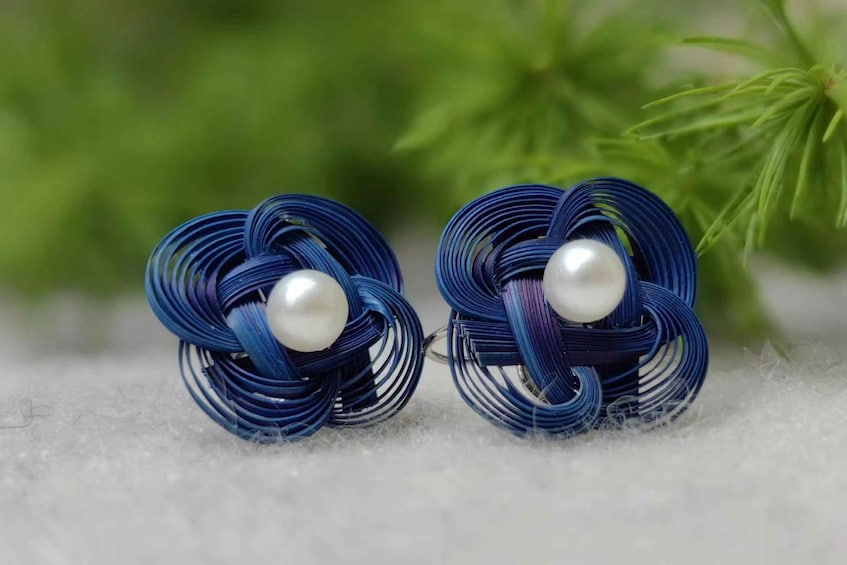 A pair of earrings with a blue wire design and a pearl. 4