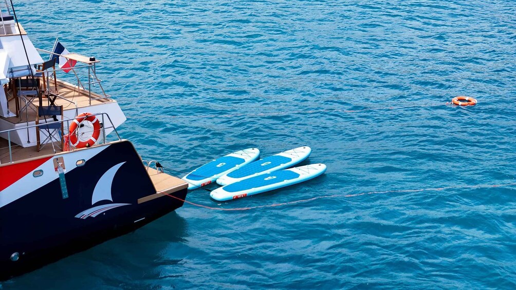 A boat with two blue paddleboards tied to its side. 2
