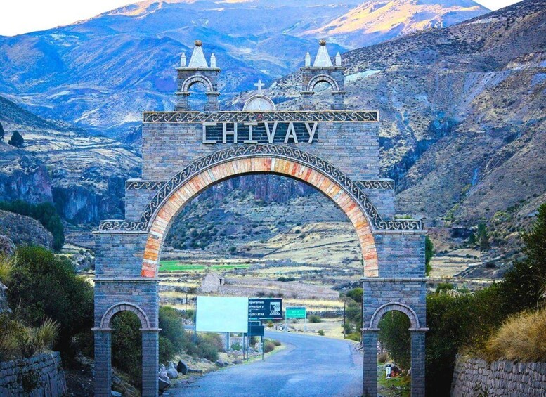 A stone archway with the word "HIVAY" inscribed on it, leading into a mountainous landscape. 1