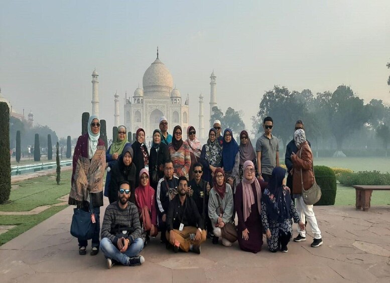 Ryhmä ihmisiä poseeraa Taj Mahalin edessä. 2