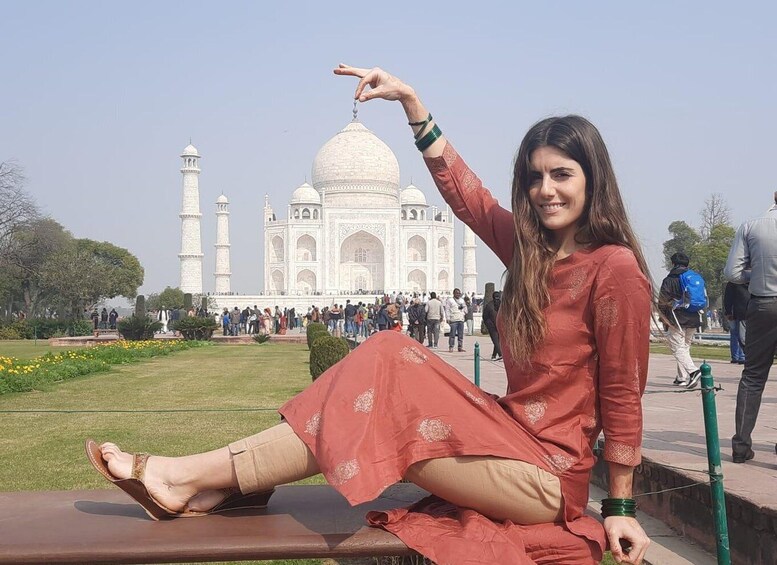 Henkilö istuu puistonpenkillä, ja taustalla näkyy Taj Mahal. 4
