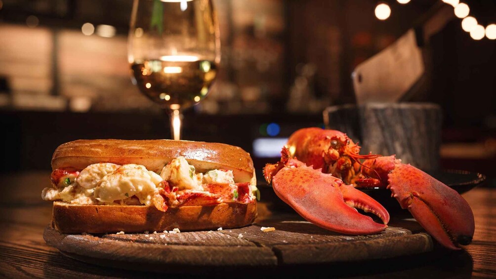 A lobster roll sandwich and a lobster tail on a wooden table. 1
