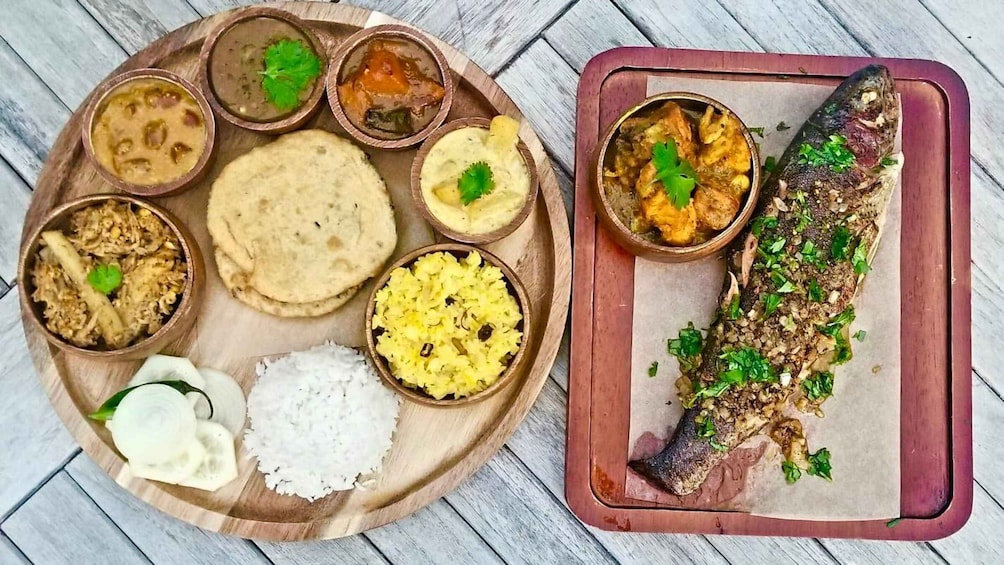 A wooden tray with various dishes including rice, flatbread, and a whole fish. 4