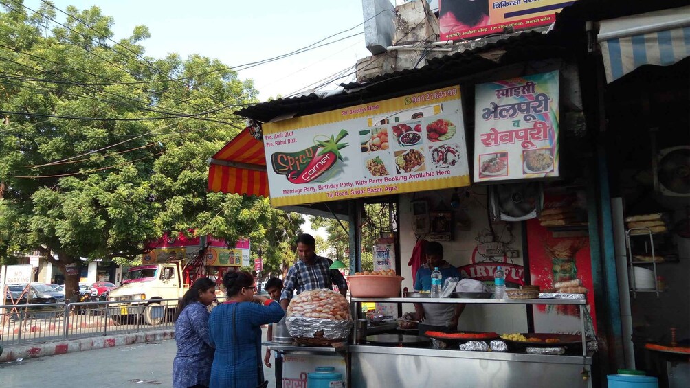 A street food stall with a signboard advertising various dishes and services. 2