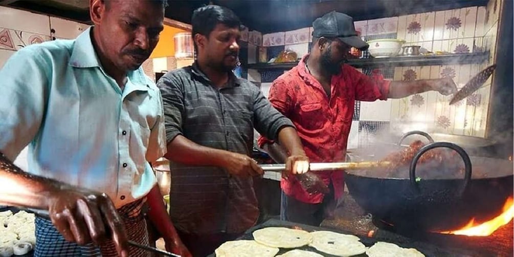 People cooking food on a large stove. 5