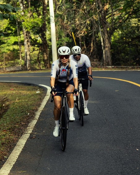 Two cyclists on a road with trees on both sides. 4