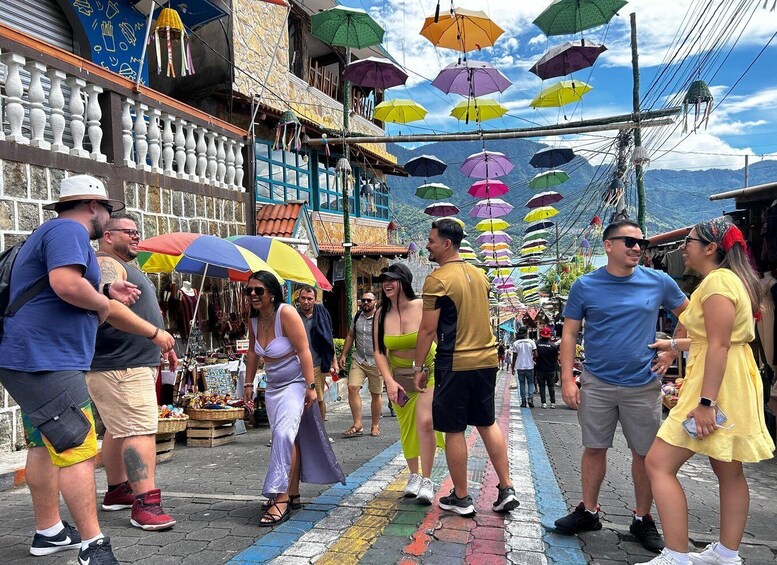 A street market with colorful umbrellas and people shopping. 5