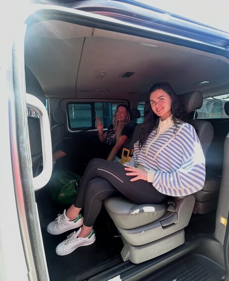 A person sitting in the back seat of a vehicle with another person in the front seat. 2