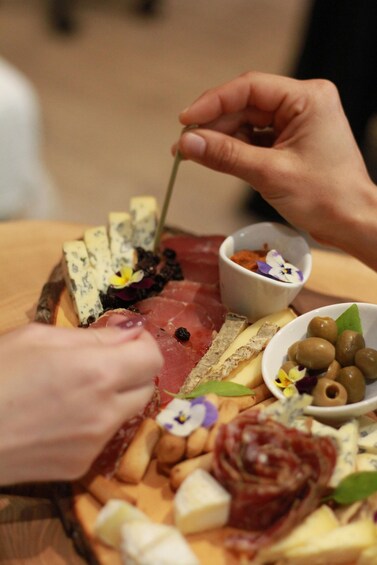 A charcuterie board with various cheeses, meats, olives, and flowers. 3