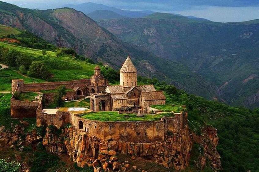 A historic fortress on a cliff with a church and surrounding lush green hills. 4
