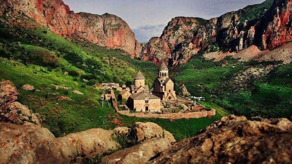 A historic church surrounded by green hills and rocky cliffs. 3