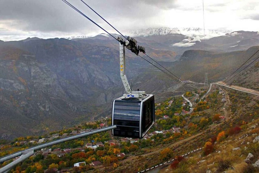 A cable car ascending a mountain with a town below. 2