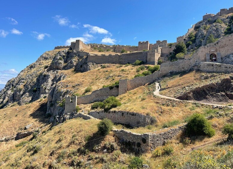 A historical stone fortification on a hillside with a clear sky. 4
