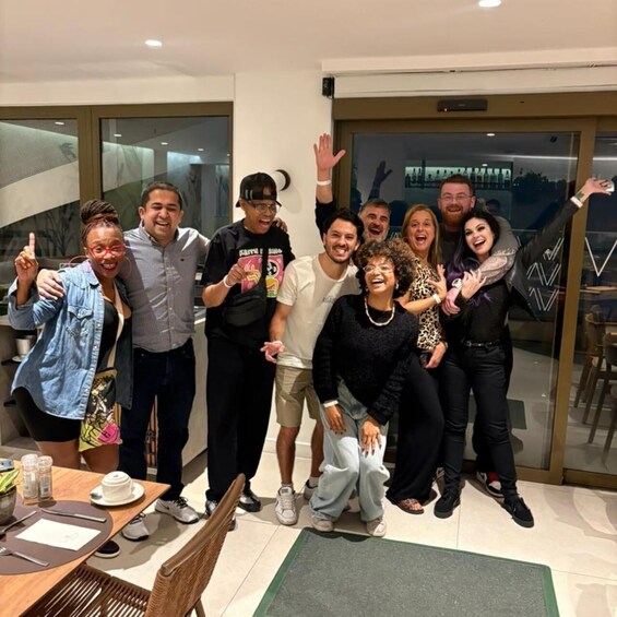 A group of people posing for a photo in a modern indoor setting with glass doors and a dining area. 5