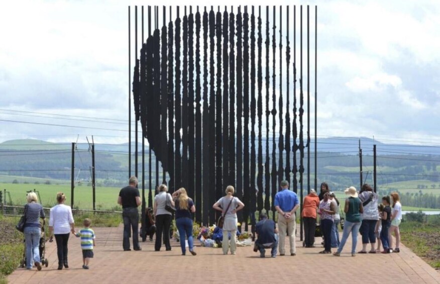 A large sculpture of a human head made of vertical poles, surrounded by people. 2