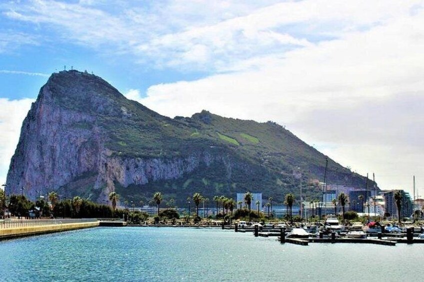 A marina with boats, a large mountain, and a clear sky. 4