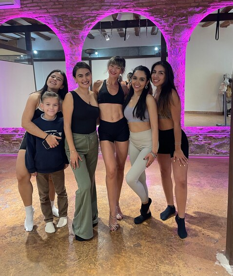 A group of people posing in a room with brick arches and purple lighting. 4