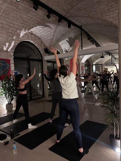 A group of people exercising in a spacious indoor area with brick walls and arched ceilings. 3