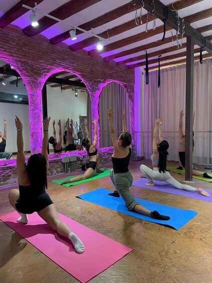 A yoga class in a studio with brick walls and wooden beams. 1