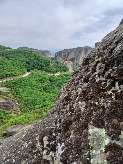 A rugged cliff with lichen, a winding road, and a distant monastery. 5