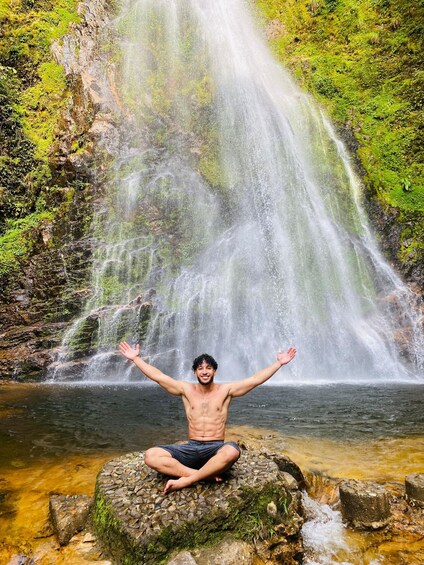Henkilö meditoi kallion päällä vesiputouksen äärellä. 3