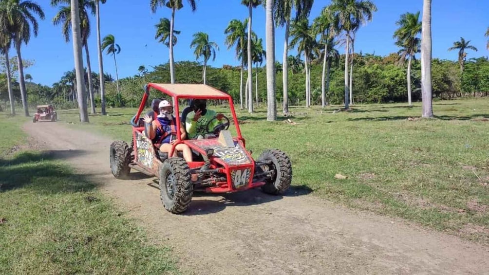 A red off-road vehicle on a dirt path with palm trees in the background. 3