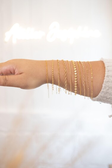 A hand wearing multiple gold bracelets. 5