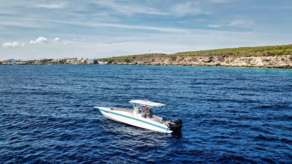 A small motorboat on a calm sea with a rocky coastline in the background. 5