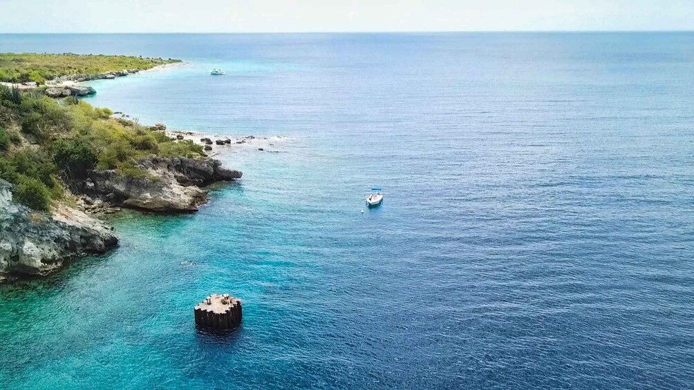 A coastal landscape with clear turquoise waters, rocky shores, and a small boat in the distance. 4