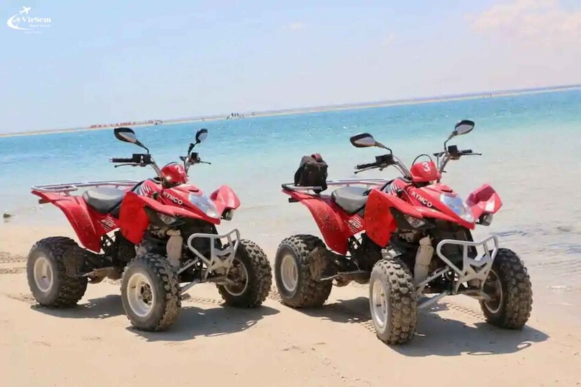 Two red ATV's parked on a sandy beach with the ocean in the background. 5