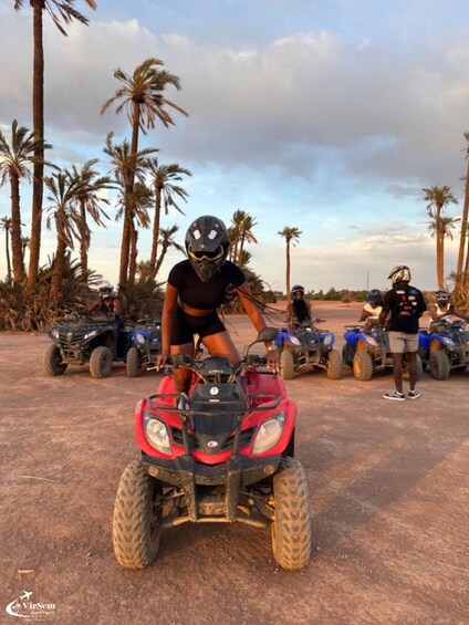 A person riding a red ATV on a dirt path with palm trees in the background. 2