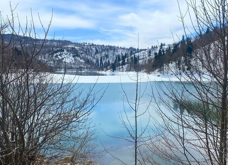 A frozen lake surrounded by snow-covered trees and hills. 4
