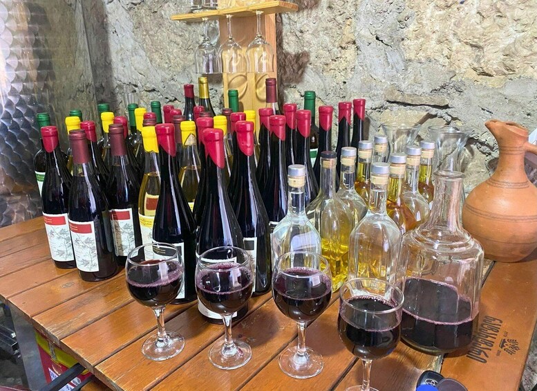 A wooden table with various wine bottles and glasses. 1
