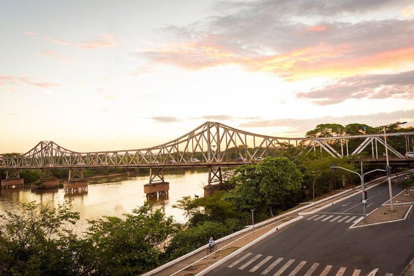 A steel bridge over a river with a sunset in the background. 3