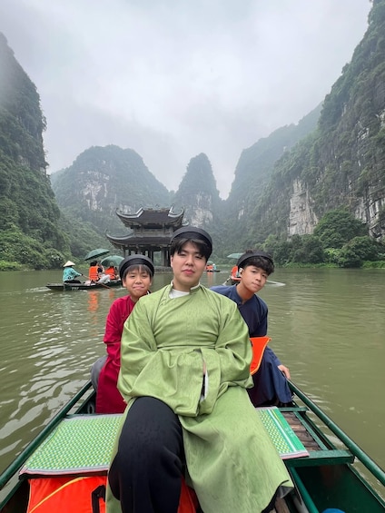 A group of people in a boat on a river with a traditional building in the background. 2