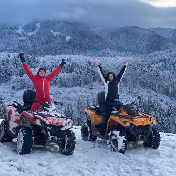 Two people on snowmobiles in a snowy mountainous area. 4