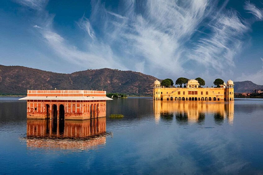 A calm lake with a reflection of a yellow building and a red-roofed structure. 3