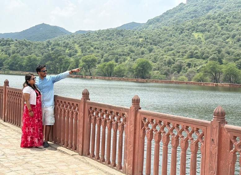 A couple standing on a bridge with a river and hills in the background. 3