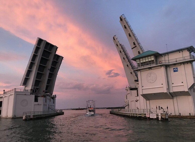 A sunset over a waterway with a bridge and a boat. 3