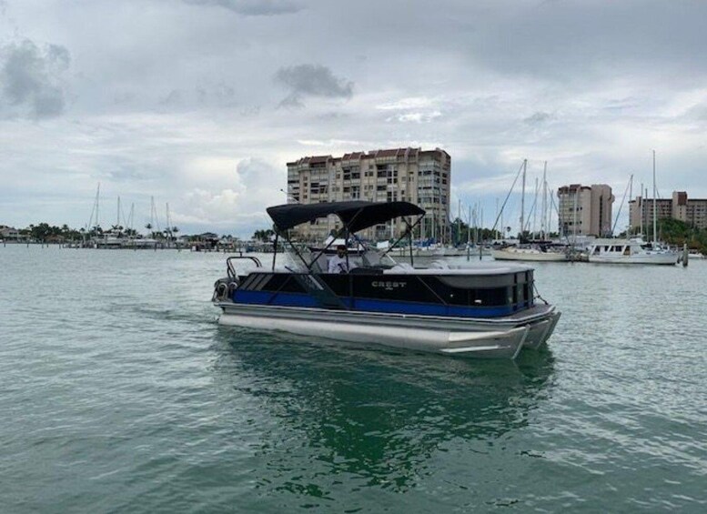A boat named 'Crest' on calm water with a marina and buildings in the background. 1