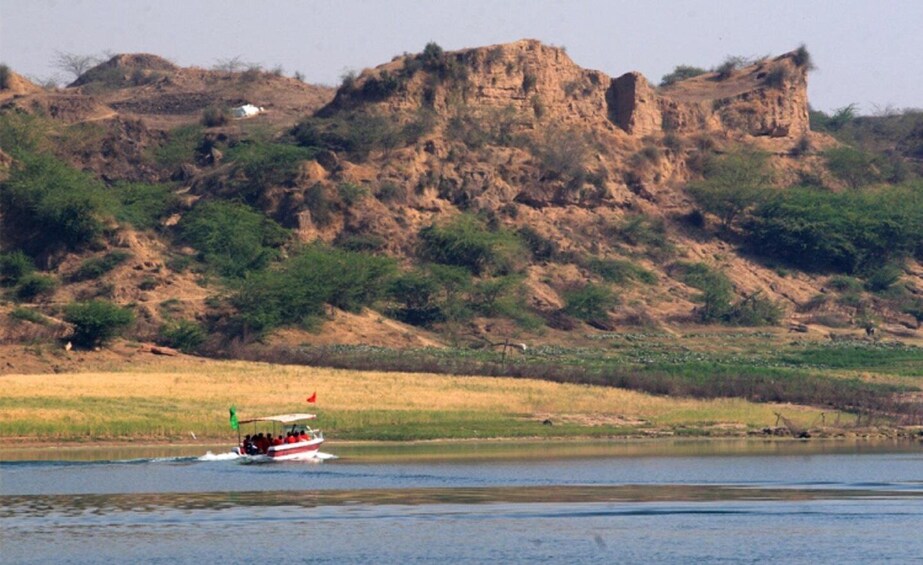 A boat on a calm river with a rocky cliff in the background. 4