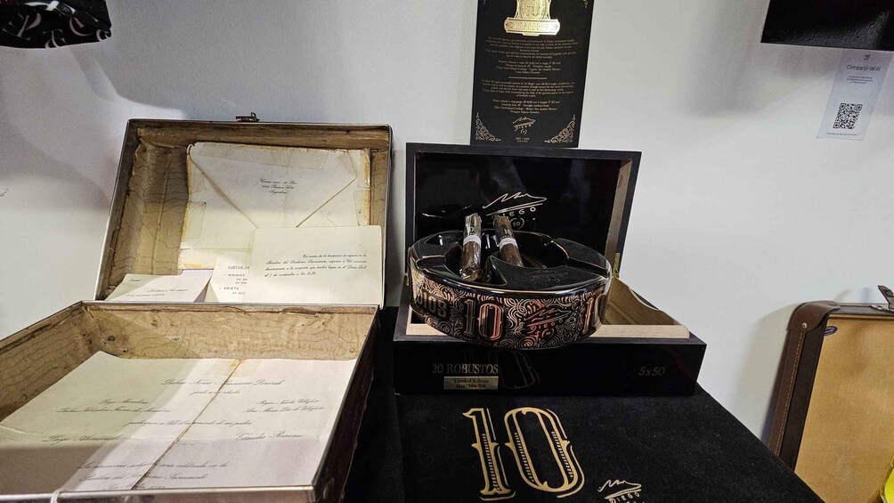 A cigar box with a limited edition label, a cigar box with cigars, and a display of documents. 4