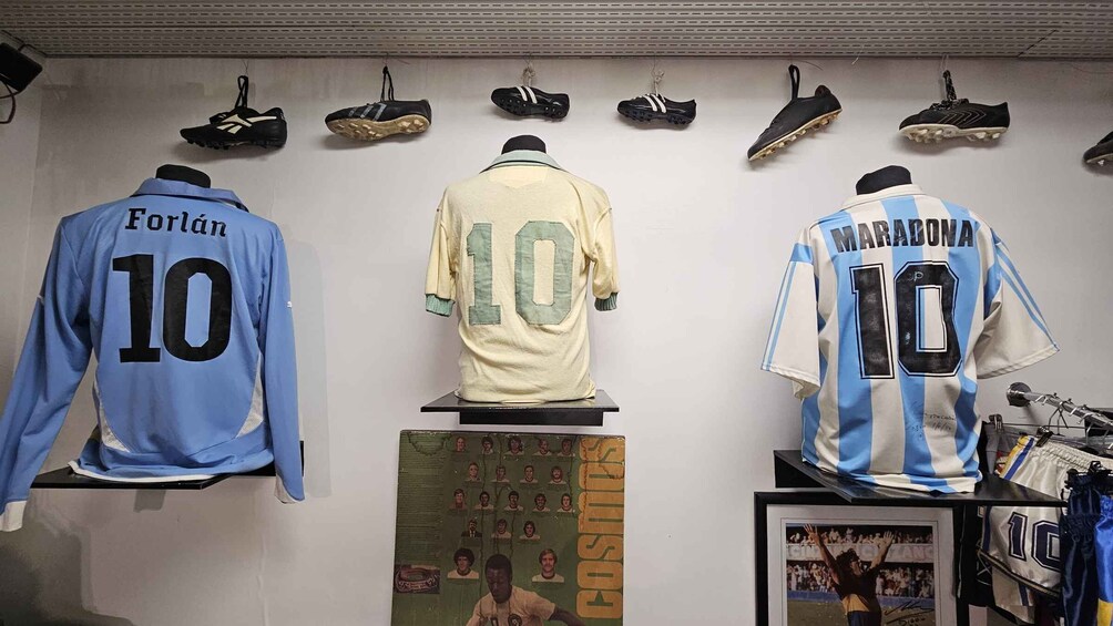 Three football jerseys with numbers 10, a display of football shoes, and a framed poster. 5