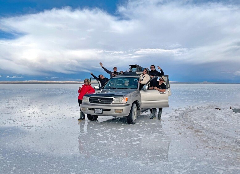 A silver pickup truck parked on a frozen lake with people standing around it. 3