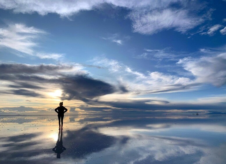 A person standing on a reflective surface with a sunset in the background. 1