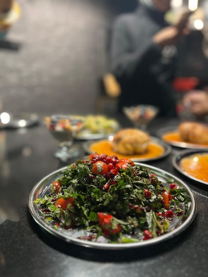 A table with various dishes, including a salad with greens and pomegranate seeds. 2