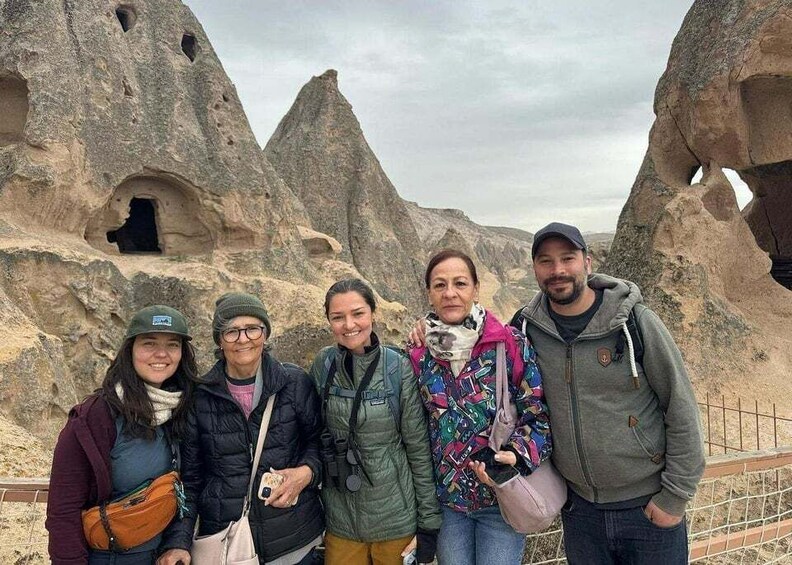 A group of people standing in front of rock formations with holes. 4
